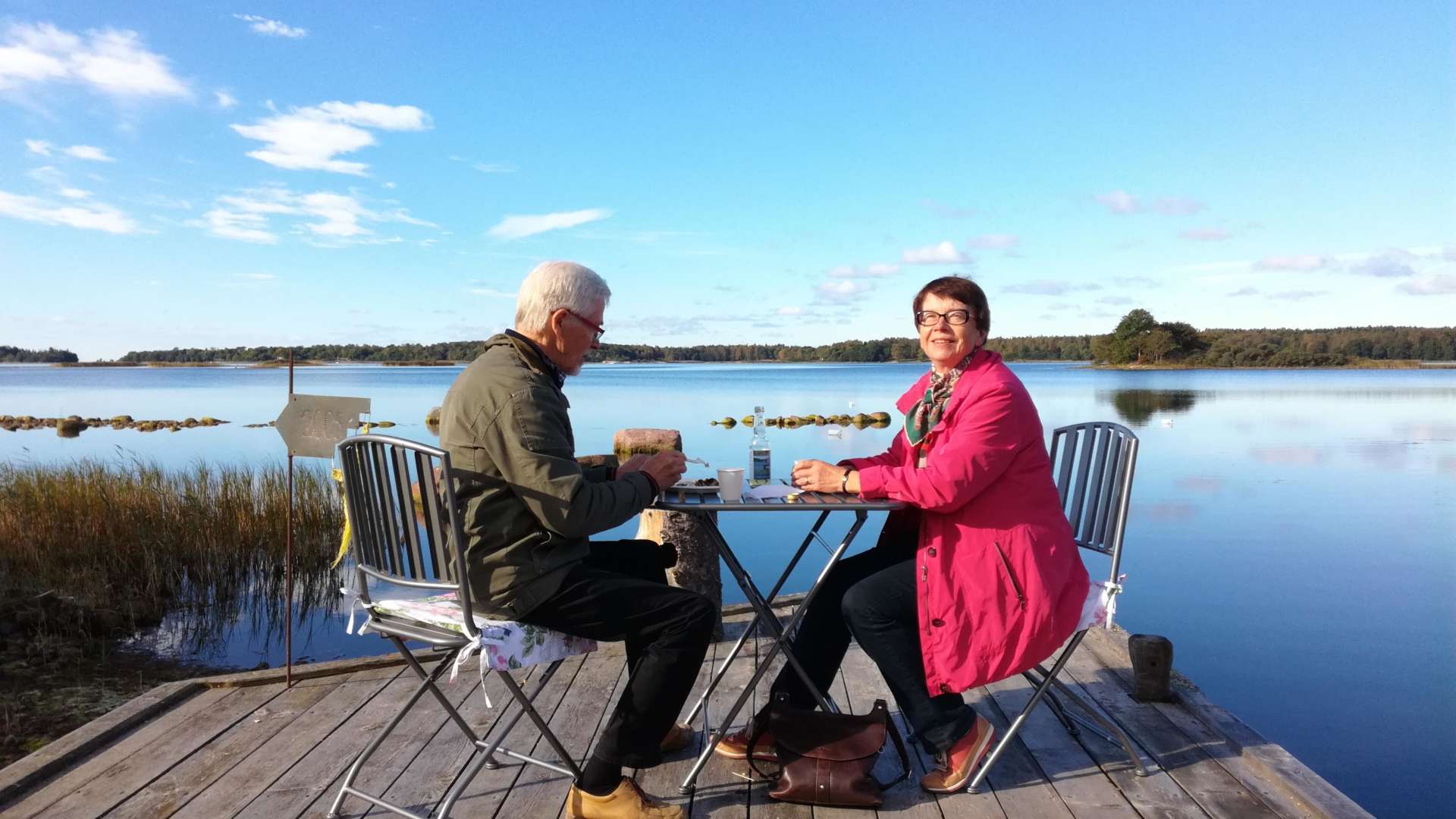 Kuvassa orivesiläiset Heikki ja Paula istuvat patiolla järven rannassa.