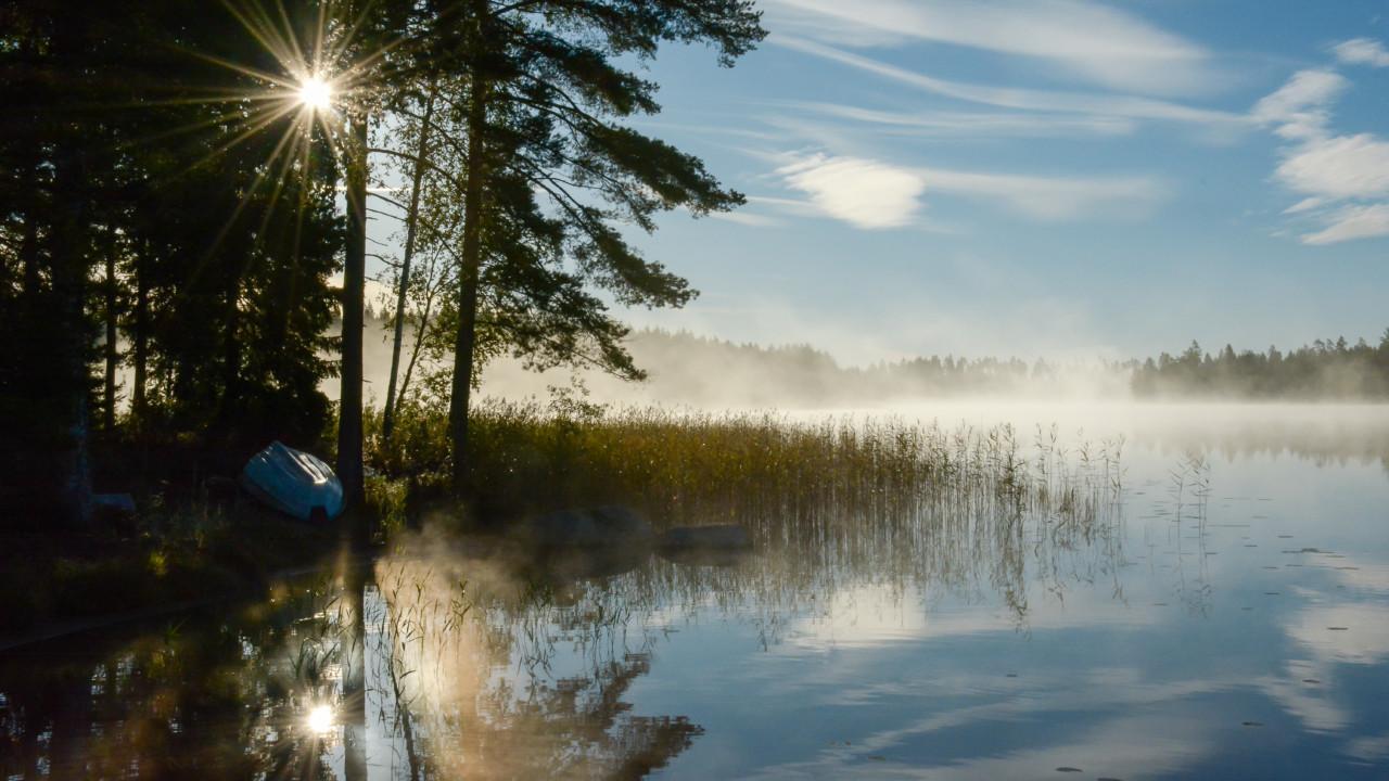 Kesäinen aamu ja soutuvene järven rannalla.