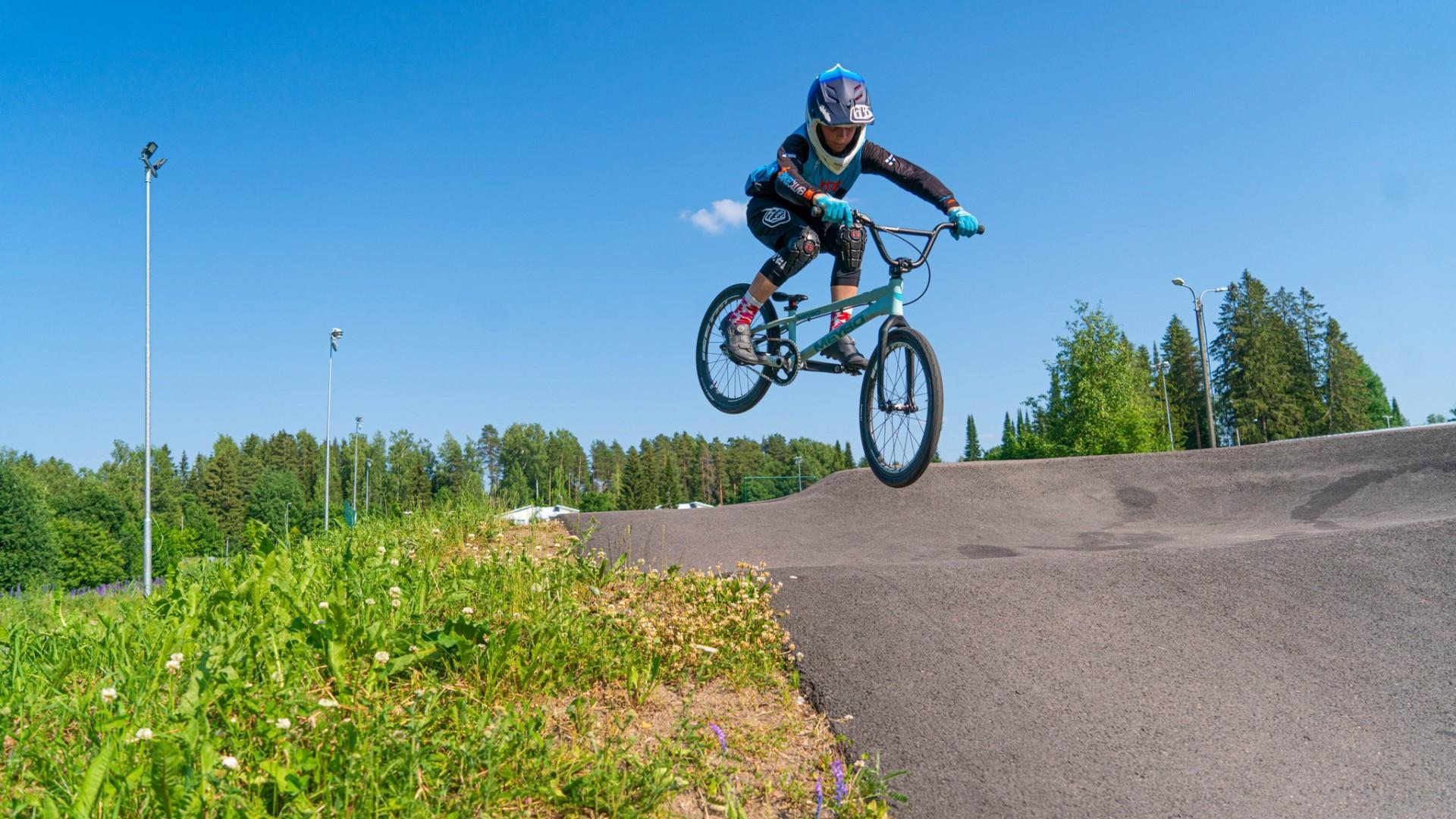 Poika hyppää BMX-pyörällä Oriparkin pumptrack-radalla.