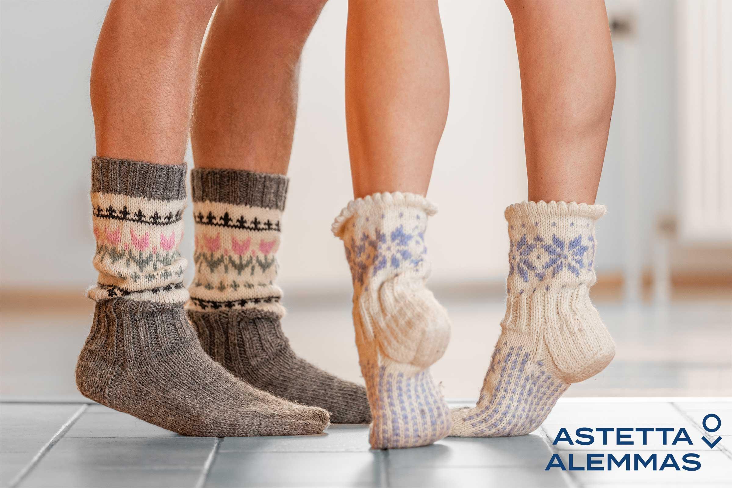Astetta alemmas -kampanjan valokuva, jossa on kaksi henkilö villasukat jalassa sekä Astetta alemmas -logo.