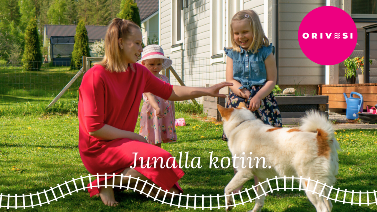 Perhe ja koira omakotitalon pihalla, junaradan kuva ja teksti Junalla kotiin.